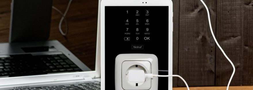 Laptop i tablet podłączone do ładowania przez kabel w gniazdku elektrycznym