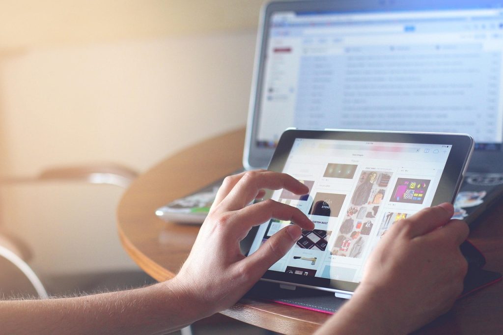 Osoba korzystająca z tabletu i laptopa jednocześnie podczas przeglądania internetu