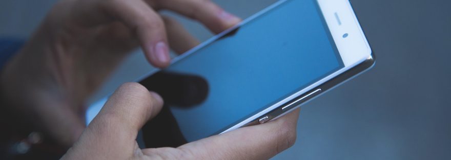 Dłonie trzymające smartfon z włączonym ekranem dotykowym