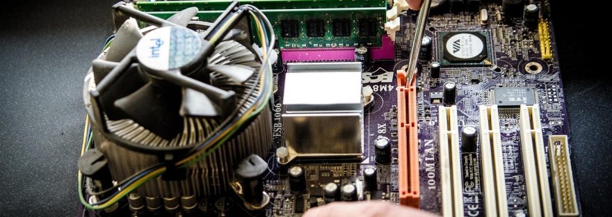 Ręce instalujące pamięć RAM na płycie głównej komputera z radiatorem procesora.​