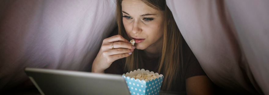 Kobieta oglada film pod koldra na laptopie